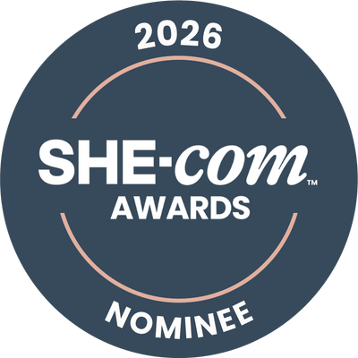 2026 SHE-COM Awards Nominee badge on a dark blue background